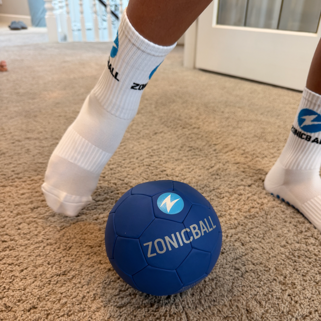 A blue ZonicBall mini soccer ball being played by person wearing ZonicBall grip socks.
